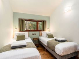 A bedroom with two single beds a small round wooden table between the beds and a window with forest view at Glentress Forest Golden Oak Treehouse Glentress Forest Peebles