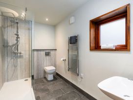 A bathroom with a shower area toilet heated towel rail window and sink at Glentress Forest Golden Oak Treehouse in Glentress Forest Peebles