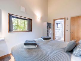 A bedroom with a bed and folded towels with window and open door to a bathroom at Keldy White Willow Premium in Keldy Forest