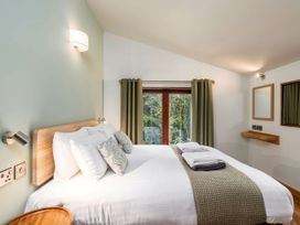 A bedroom with a double bed pillows and folded towels by a window with curtains at Strathyre Golden Oak Treehouse in Strathyre Ben Ledi