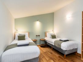 A bedroom with two single beds side by side with round wooden bedside tables at Strathyre Golden Oak Treehouse in Strathyre Ben Ledi