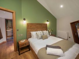 A bedroom with a wooden bed and green accent wall at Strathyre Golden Oak Treehouse in Strathyre Ben Ledi