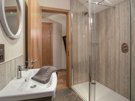 A bathroom with a shower enclosure a sink with a towel and a round mirror at Strathyre Golden Oak Treehouse Strathyre Ben Ledi