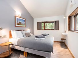 A bedroom with a made bed and folded towels on it with windows on two walls at Strathyre White Willow Premium in Strathyre Ben Ledi