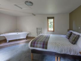 A bedroom with a bed and a bathtub next to the window at Keldy Golden Oak Cottage in Keldy Forest