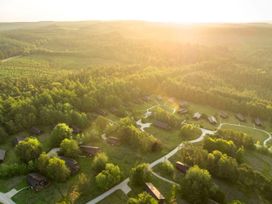 Aerial view of wooden cabins surrounded by trees and pathways in a forest during sunset at Cropton Golden Oak in Cropton Forest