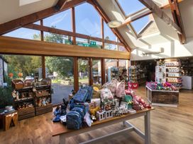 A gift shop with backpacks and toys on display tables near large windows and skylights at Cropton Golden Oak in Cropton Forest
