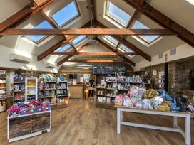 A retail store interior with wooden beams skylights shelves and tables displaying various merchandise at Cropton Golden Oak in Cropton Forest