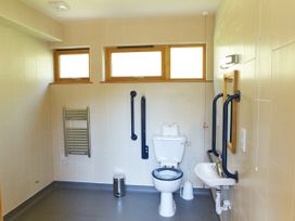 A wheelchair accessible bathroom with a toilet sink grab bars and windows at Thorpe Forest Silver Birch wheelchair accessible cabin in Thorpe Forest