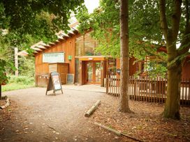 The entrance of a wooden building with signs and trees in the foreground at Thorpe Forest Silver Birch wheelchair accessible cabin in Thorpe Forest