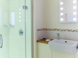A bathroom with a glass shower enclosure and a wall-mounted sink with toiletries at Glentress Forest Silver Birch Glentress Forest Peebles