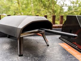 An outdoor countertop with a small oven and a pizza peel on a patio at Glentress Forest White Willow Premium in Glentress Forest Peebles