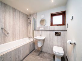 A bathroom with a bathtub shower combination sink toilet and a window at Glentress Forest Golden Oak in Glentress Forest Peebles