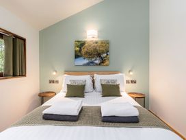 A bedroom with a double bed white and green pillows two towels on the bed wooden side tables a landscape picture on the green wall Glentress Forest Golden Oak Glentress Forest Peebles
