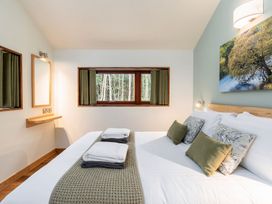 A bedroom with a bed and folded towels on it and a window with curtains at Glentress Forest Golden Oak in Glentress Forest Peebles