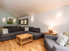 A living room with gray sofas a wooden coffee table and a dining table in the background at Glentress Forest Golden Oak in Glentress Forest Peebles