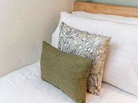 A bed with white sheets and two decorative pillows one with a leaf pattern and the other plain green at Glentress Forest Golden Oak Glentress Forest Peebles