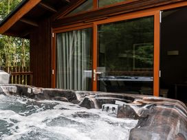 A bubbling hot tub outside a wooden cabin with glass sliding doors at Glentress Forest Golden Oak in Glentress Forest Peebles