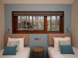 A bedroom with two single beds and a small round wooden table under a window showing trees at Thorpe Forest Silver Birch in Thorpe Forest