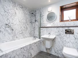 A bathroom with a bathtub shower sink toilet and a round mirror at Glentress Forest White Willow Premium in Glentress Forest Peebles