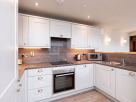 A kitchen with white cabinets a built in oven a stovetop a kettle a microwave and a sink at Glentress Forest White Willow Premium in Glentress Forest Peebles