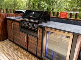 An outdoor kitchen area with a built-in grill oven and a glass-front refrigerator surrounded by wood paneling