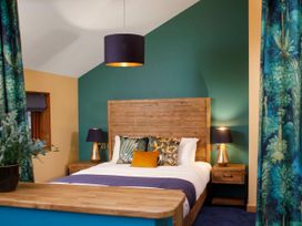 A bedroom with a wooden bed frame and headboard with decorative pillows and bedside tables with lamps at Garwnant Golden Oak Hideaway in Garwnant Bannau Brycheiniog Brecon Beacons