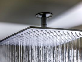A metal square rain shower head mounted on a ceiling with water flowing at Glentress Forest Golden Oak Hideaway Glentress Forest Peebles