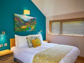 A bedroom with a bed against a teal wall with a painting above at Beddgelert Golden Oak - freshly inspired design Beddgelert Eryri Snowdonia