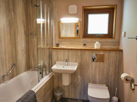 A bathroom with a bathtub shower combination sink toilet mirror and window at Beddgelert Golden Oak - freshly inspired design Beddgelert Eryri Snowdonia