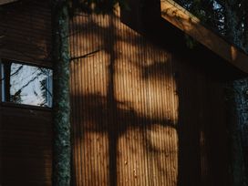 A wooden cabin wall with shadows of tree branches and a window at Glentress The Unfurl Cabin (2 Bed) Glentress Forest Peebles