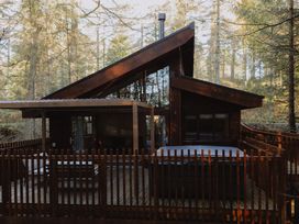 A wooden cabin with deck and outdoor seating surrounded by trees at Glentress The Unfurl Cabin (2 Bed) Glentress Forest Peebles
