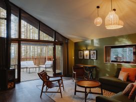 A living room with chairs a sofa a coffee table pendant lights and a deck with outdoor seating at Glentress The Unfurl Cabin 2 Bed in Glentress Forest Peebles