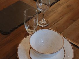 A wooden table with a bowl and plates stacked beside two drinking glasses at Glentress The Unfurl Cabin (2 Bed) Glentress Forest Peebles