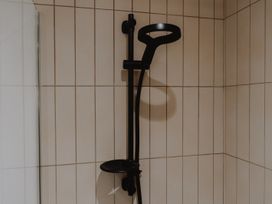 A black shower head and control mounted on a tiled bathroom wall at Glentress The Unfurl Cabin (2 Bed) Glentress Forest Peebles