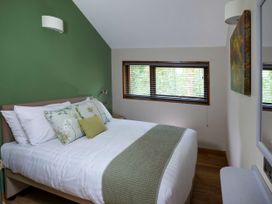 A bedroom with a bed green accent wall and a window with blinds at Delamere Forest Golden Oak (2 doubles and 1 twin) in Delamere Forest