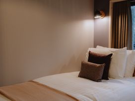 A bed with white sheets pillows and a beige blanket in a bedroom at Glentress The Unfurl Cabin 4 Bed Glentress Forest Peebles