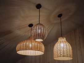 Three hanging wicker pendant lamps on a ceiling in a room with wooden panel walls at Glentress The Unfurl Cabin 4 Bed Glentress Forest Peebles