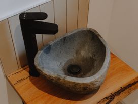 A stone sink with a black faucet on a wooden countertop at Glentress The Unfurl Cabin (4 Bed) in Glentress Forest Peebles
