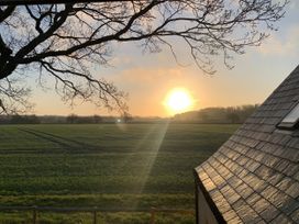 A sunset view over a field with trees and a building roof at 4 Wellacres Cottage Draycott near Moreton-In-Marsh