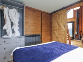 A bedroom with robes on a hanger and a fireplace at Squirrel's Nest in South Luffenham near Edith Weston