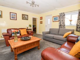 A living room with two brown leather sofas a gray sofa a wooden coffee table and framed pictures on yellow walls at Millers Cottage in Old Malton near Malton