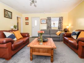 A living room with two brown leather sofas and a gray sofa around a wooden coffee table with flowers at Millers Cottage Old Malton near Malton