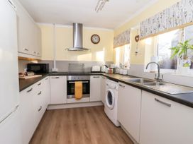 A kitchen with white cabinets black countertops a washing machine oven and sink at Millers Cottage in Old Malton near Malton