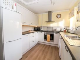 A kitchen with white cabinets a refrigerator oven microwave toaster kettle and sink at Millers Cottage in Old Malton near Malton