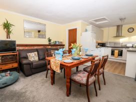 A dining area with a set table and chairs next to a brown sofa and a kitchen with white cabinets at Millers Cottage in Old Malton near Malton