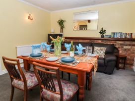 A dining room with a wooden table set for six people with blue plates and napkins a sofa a mirror a small bookshelf and a plant at Millers Cottage in Old Malton near Malton