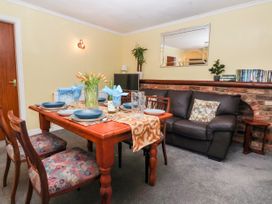 A dining table set with plates and napkins next to a sofa with a cushion and a mirror on the wall at Millers Cottage in Old Malton near Malton