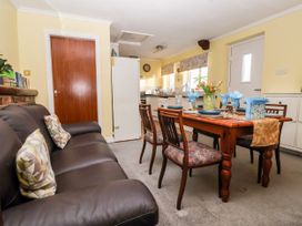 A kitchen dining area with a wooden table set for four and a brown leather sofa with cushions at Millers Cottage Old Malton near Malton