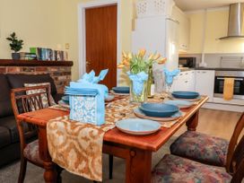 A dining table set with blue plates and napkins flowers on table in a room with kitchen and sofa at Millers Cottage in Old Malton near Malton